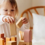 Enfant concentré jouant avec des blocs en bois selon la méthode Montessori