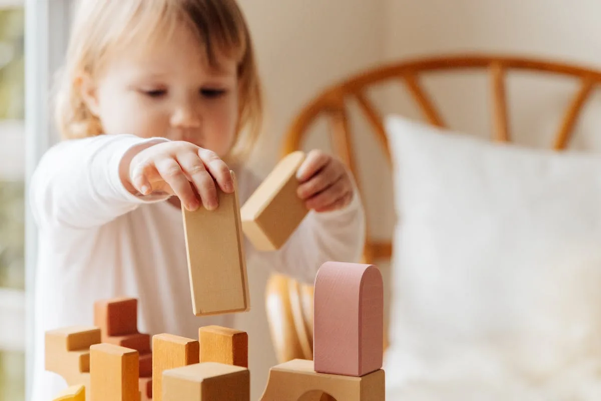 Enfant concentré jouant avec des blocs en bois selon la méthode Montessori