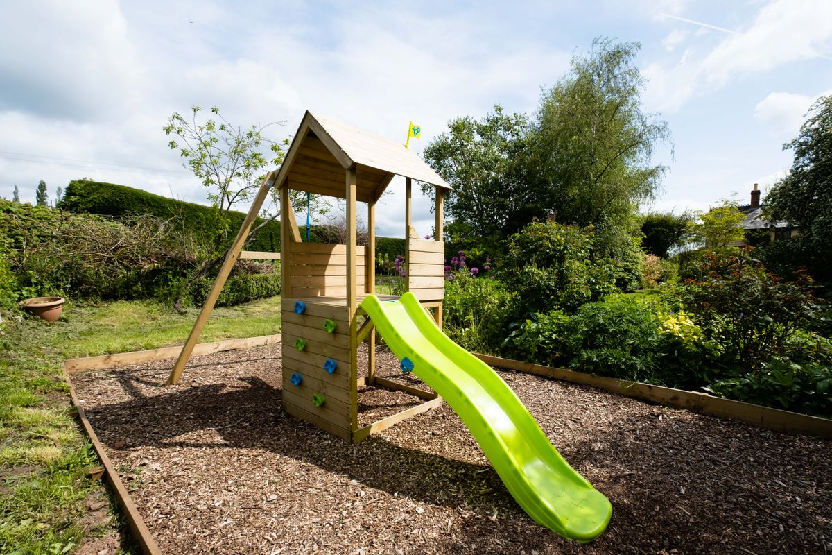 cabane enfant en bois avec toboggan intégré dans un jardin