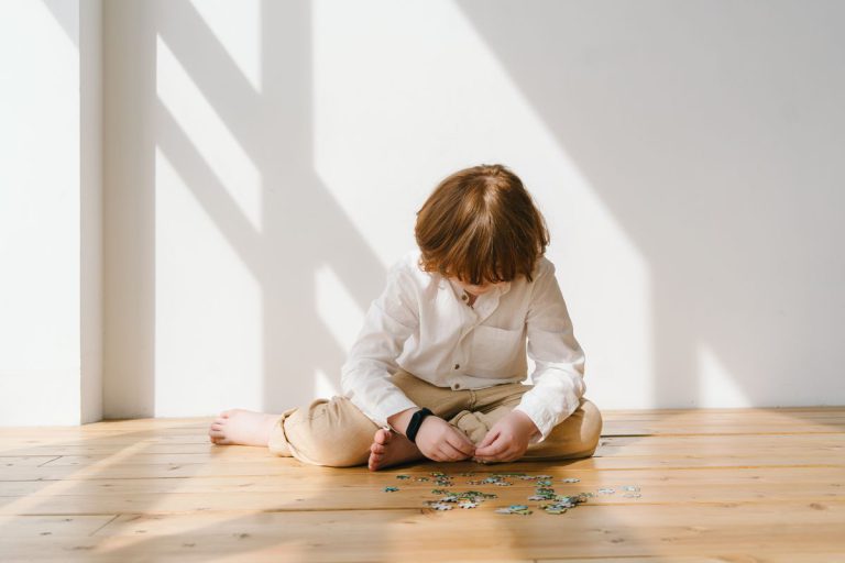 Enfant de 2 ans assemblant un puzzle en bois coloré